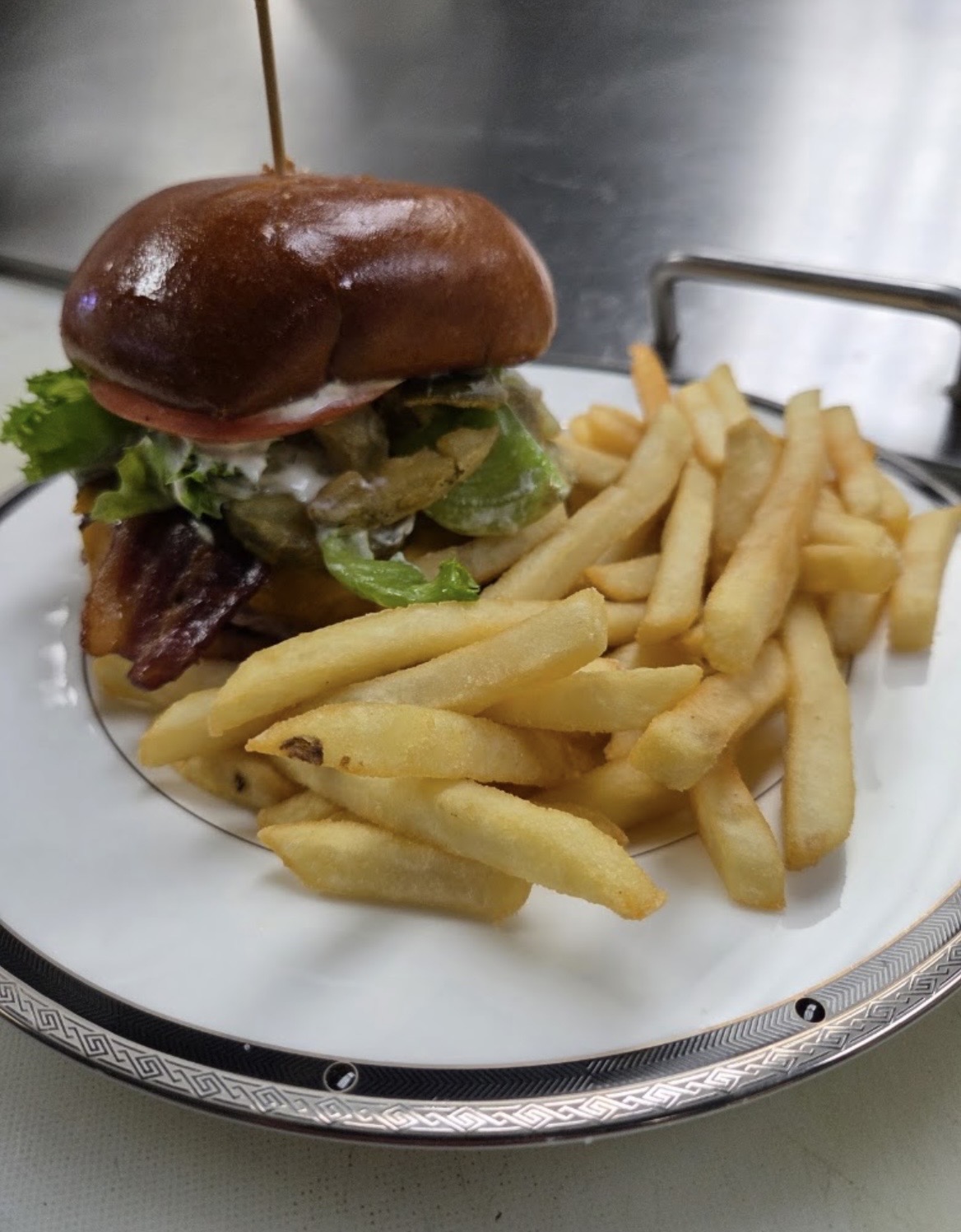 Bacon cheese burger on a brioche bun with a side of fries
